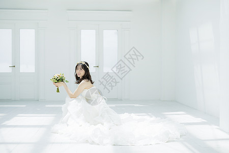 蹲坐在地上拿着手捧花的婚纱美女图片
