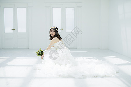 蹲坐在地上拿着手捧花的婚纱美女图片