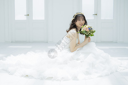 蹲坐在地上拿着花束微笑的婚纱美女图片