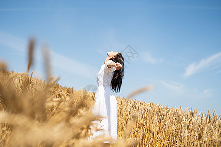 麦田里张开双臂的呼吸的年轻女子图片