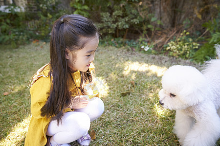 小女孩和狗狗在花园玩耍图片