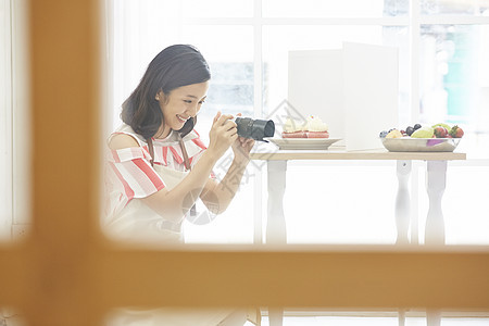 年轻女子拿着相机拍自制甜品图片