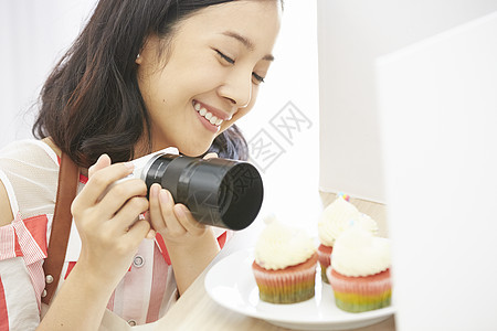 拿着相机拍甜品的年轻女子图片
