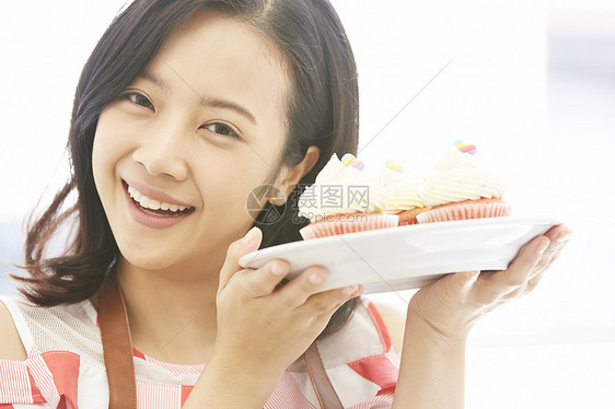 年轻女子微笑的举着自制烘焙蛋糕图片