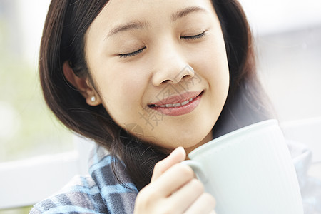 拿着咖啡闭眼微笑的年轻女子图片