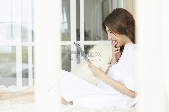 看着平板电脑开心的女青年图片