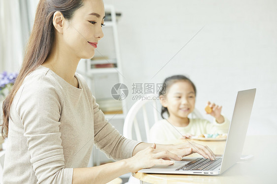 年轻女人在家带孩子居家办公图片