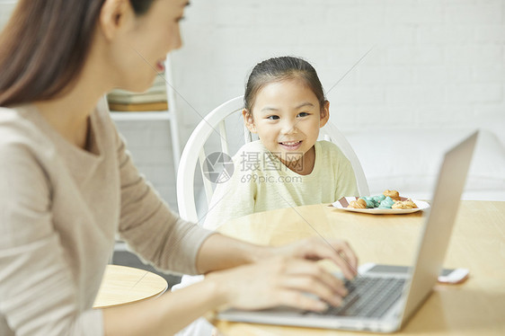 年轻女人在家带孩子居家办公图片