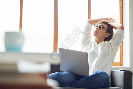 休闲职业女人在沙发上拿着电脑思考图片