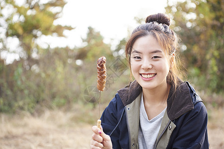 露营地吃烤串的女人形象图片