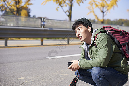 蹲在路边等车的青年男子图片