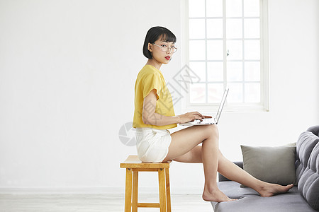 居家坐在椅子上使用笔记本电脑的年轻女子图片