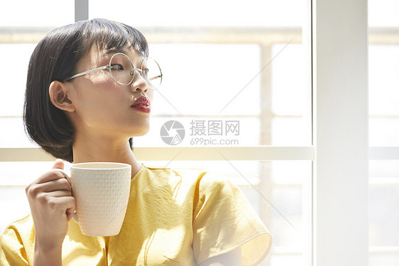 女人在窗边放松喝茶图片