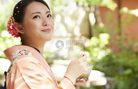 在茶馆穿桃红色和服吃甜点的妇女图片