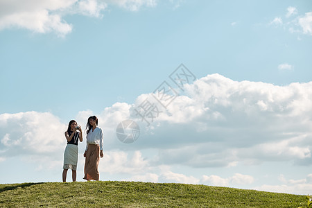 两个女人在户外开心用相机拍照图片