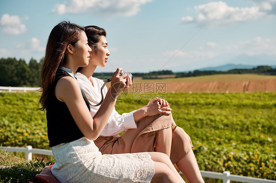 两个女人在户外开心用相机拍照图片