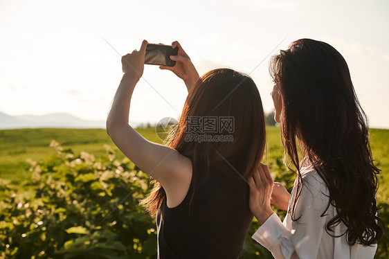 两个女人在户外开心用手机拍照图片