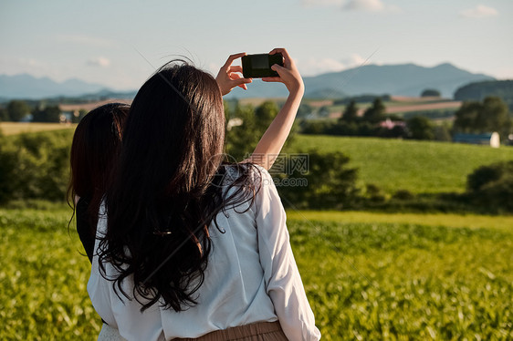 两个女人在户外开心用手机拍照图片