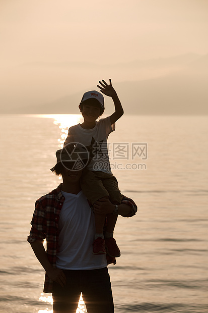 暮色湖边沙滩上游玩的父子图片