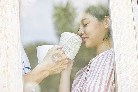 窗口低头喝咖啡的年轻女子图片