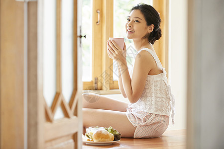 居家吃早餐拿着咖啡的年轻女子图片