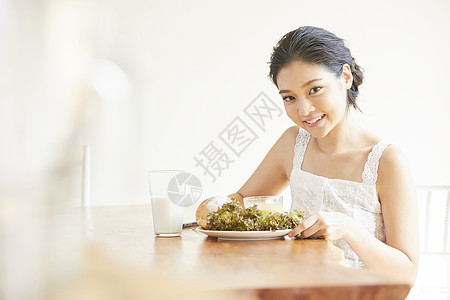 餐桌吃早餐微笑的年轻女子图片