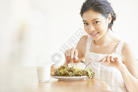 使用刀叉吃早餐的年轻女子图片