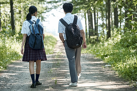 男生帮女生拉拉链早晨女高中生和男同学走路上学背景