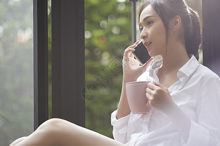 坐在窗边喝茶的年轻居家女性图片