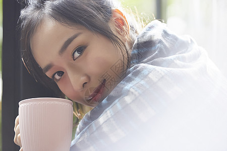 坐在窗边喝茶的年轻居家女性图片