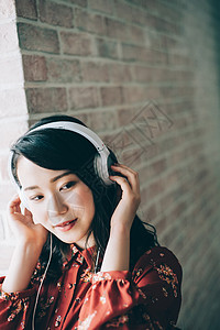 青年亚洲人放松用耳机听音乐红色一件女人图片