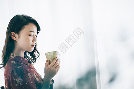 20多岁年轻女女坐在与杯子的一把椅子的一个红色单件夫人图片