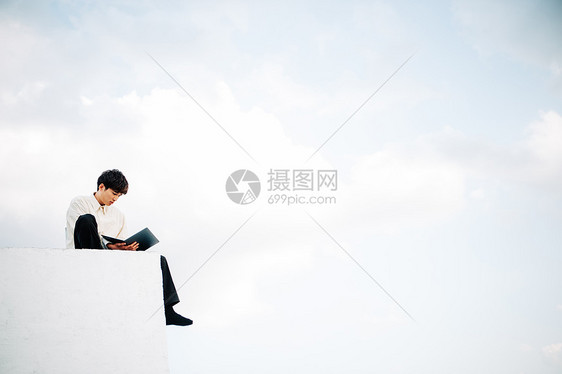 一个男人坐在屋顶上打开笔记本电脑图片
