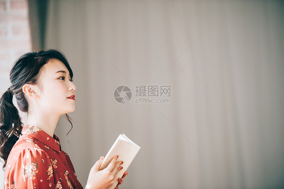 坐在窗户边沙发上读书的女士图片