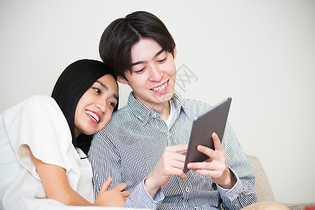 一对夫妇在沙发上放松看平板电脑图片
