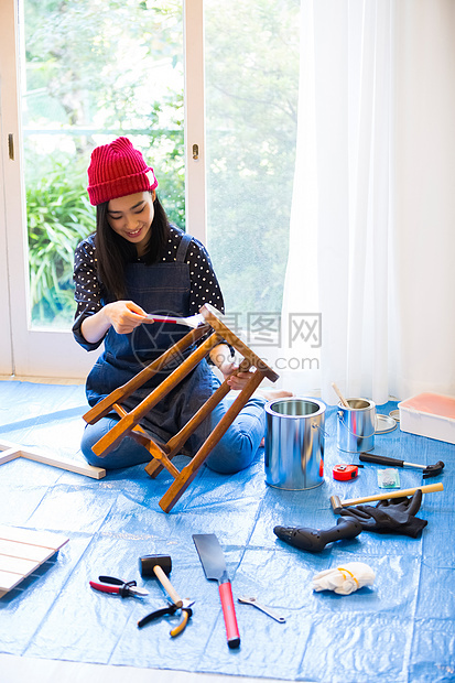 给凳子刷涂料的女青年图片