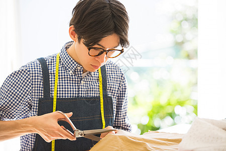 男子用剪刀裁剪布料图片