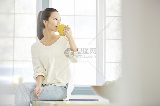 女人端着水杯喝水图片
