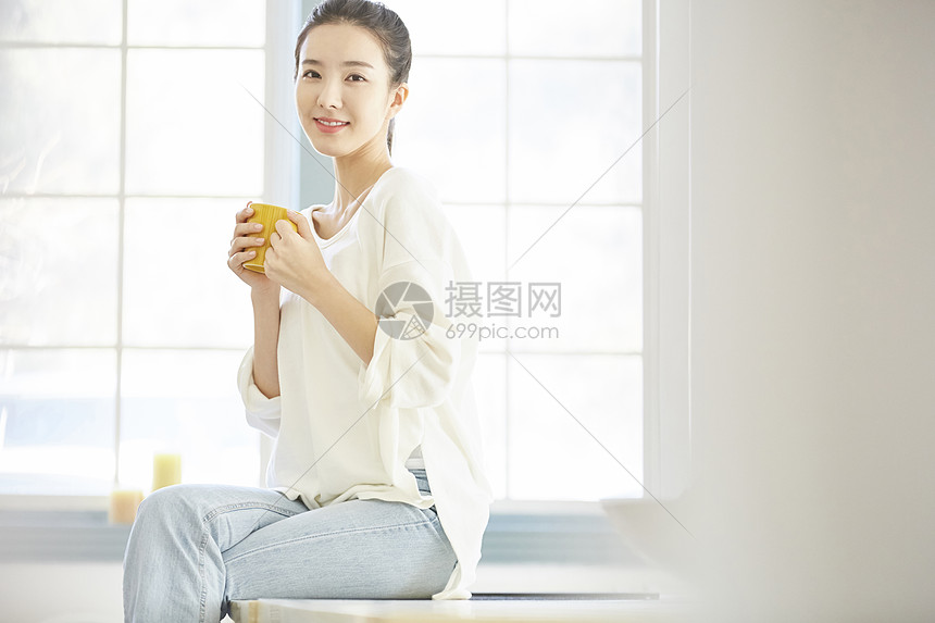 女人端着水杯喝水图片