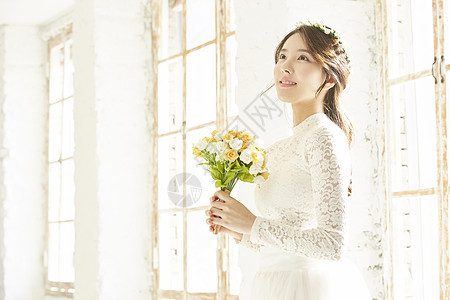 窗边拿着手捧花的美丽新娘图片