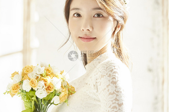 窗边拿着手捧花的美丽新娘图片
