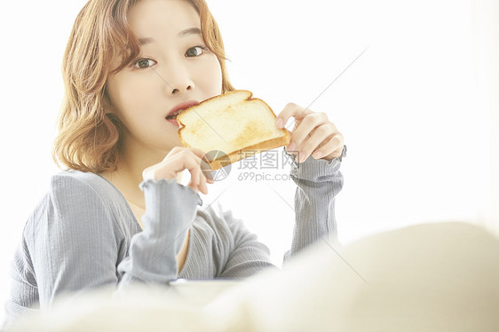 早餐吃着土司的女青年图片