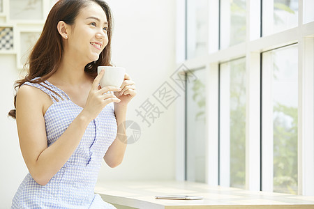 坐在窗边喝咖啡的年轻女子图片