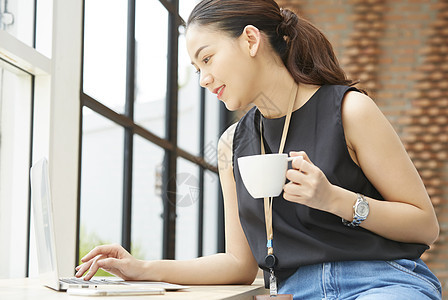 坐在窗台边上办公的女性图片