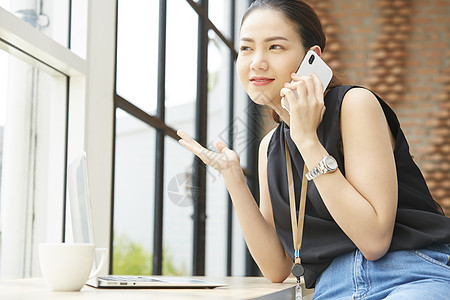 坐在窗台边上接打电话的女性图片