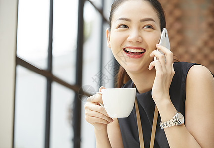 坐在窗台边上接打电话的女性图片