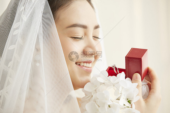 戴着头纱手拿钻戒的新娘图片