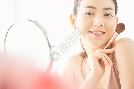 坐在镜子前美容护肤的年轻女性图片