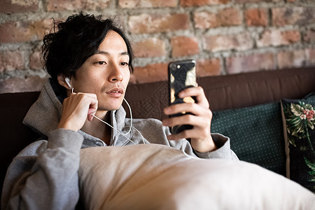 戴着耳机看手机的成年男子图片