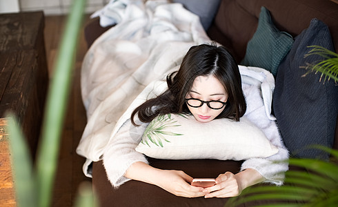 趴在沙发上看着手机的女人图片素材